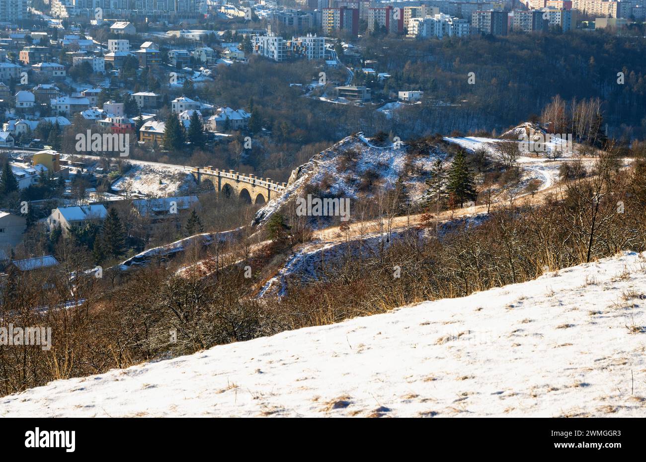 Vecchio viadotto ferroviario nel quartiere cittadino di Hlubocepy e edificio lì, si affaccia dalla collina con prato innevato in inverno. Praga, repubblica Ceca. Foto Stock