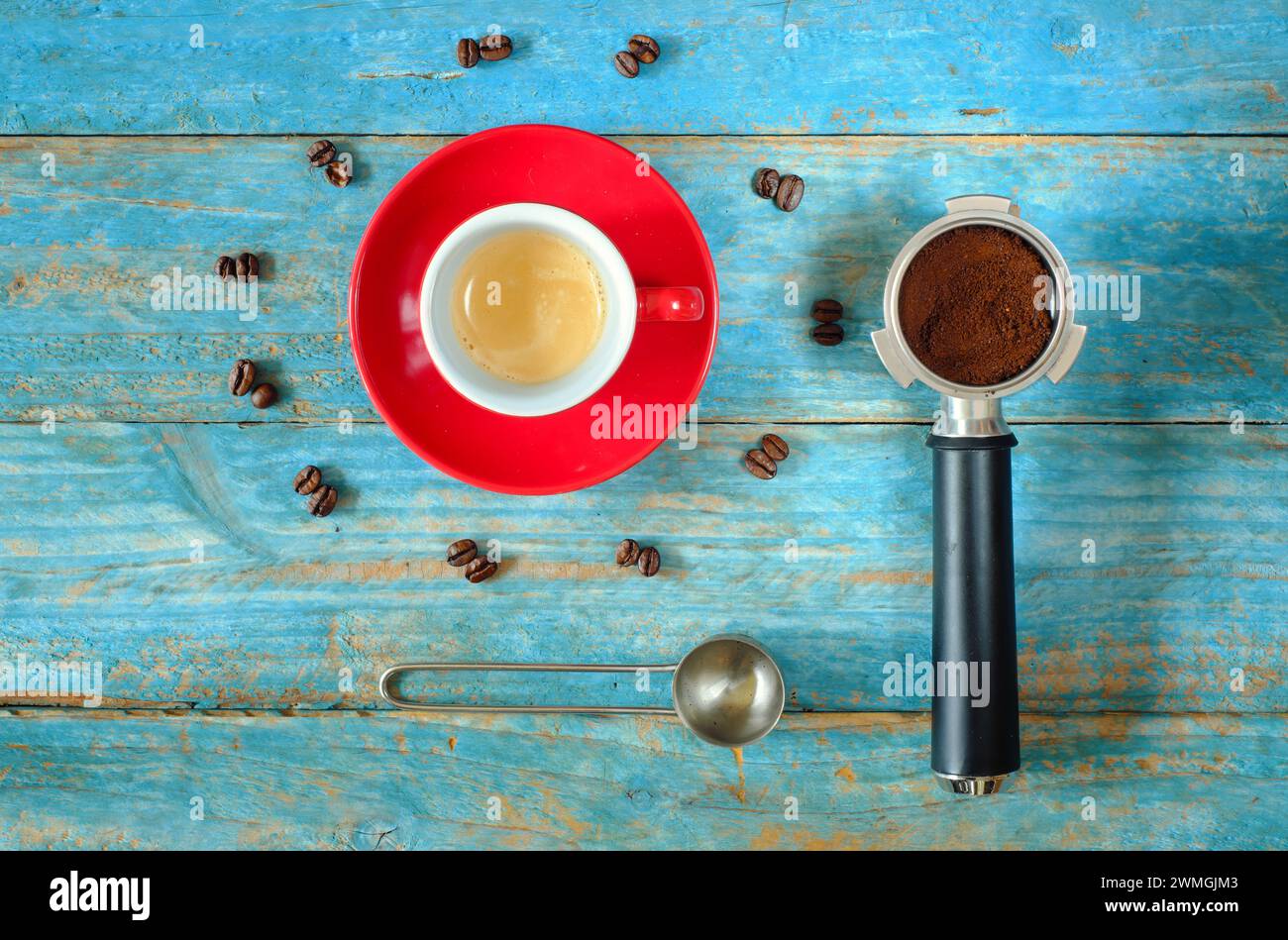 tazza di caffè espresso appena preparato con portafiltro, chicchi di caffè e cucchiaio, piatto, spazio per le copie gratuito Foto Stock