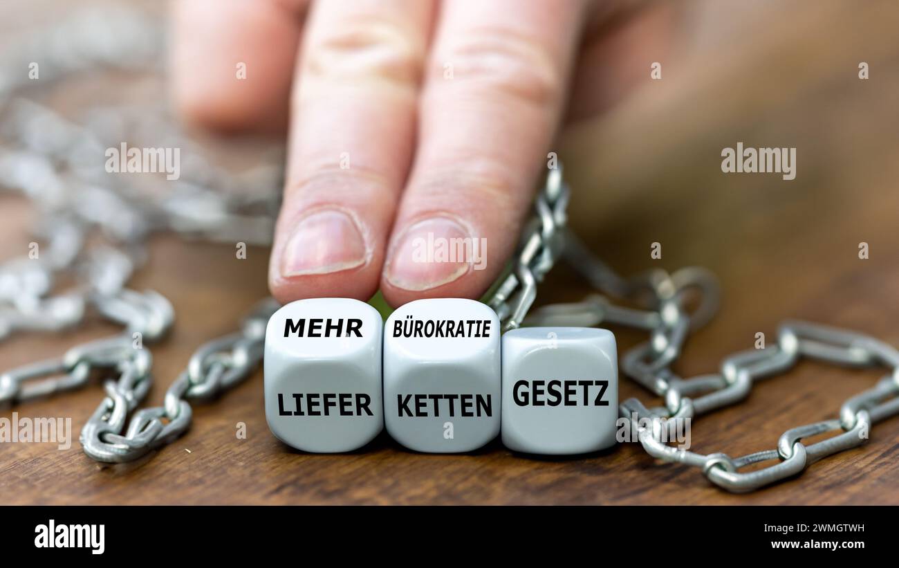 La mano gira i dadi e cambia l'espressione tedesca "Lieferkettengesetz" (legge sulla catena di approvvigionamento) in "mehr buerokratie Gesetz" (legge sulla burocrazia). Foto Stock