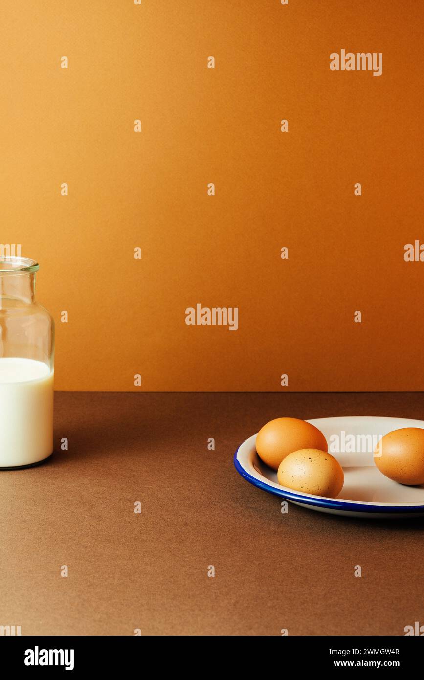 Tre uova con latte nel biberon di vetro su sfondo marrone, riprese in studio con ombre nitide e contrasto elevato Foto Stock