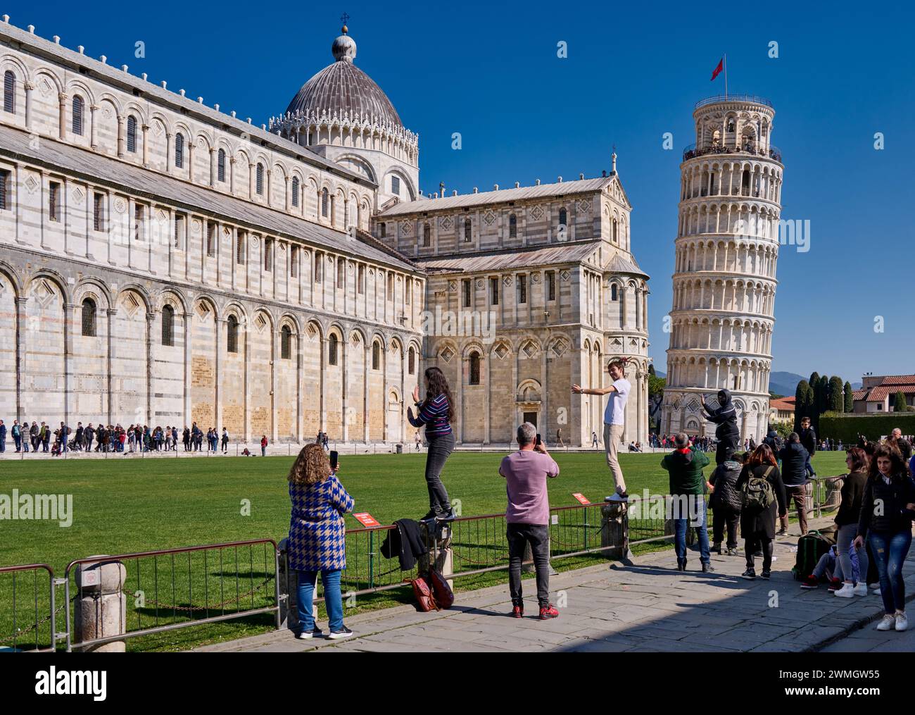 I turisti cercano di tenere simbolicamente la Torre Pendente di Pisa, Toscana, Italia Foto Stock