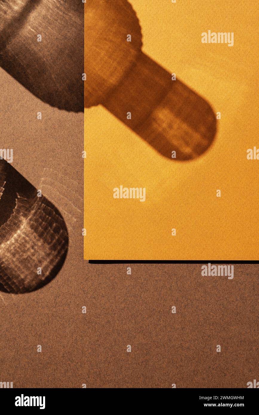 Ombra di vetro e fondo su sfondo marrone e arancione. Luce diretta con ombre lunghe. Direttamente sopra, vista ad angolo alto. Foto Stock