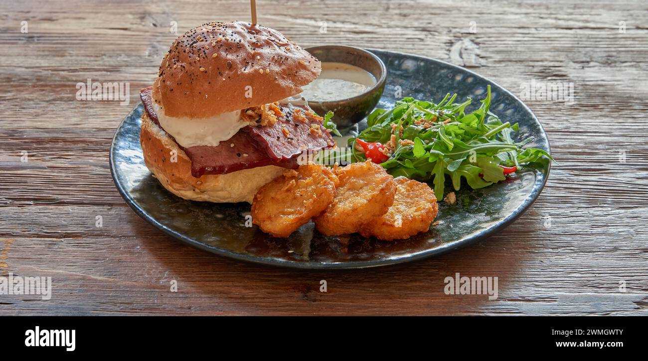 Piatto con hamburger di maiale e rosti su un tavolo in legno testurizzato Foto Stock