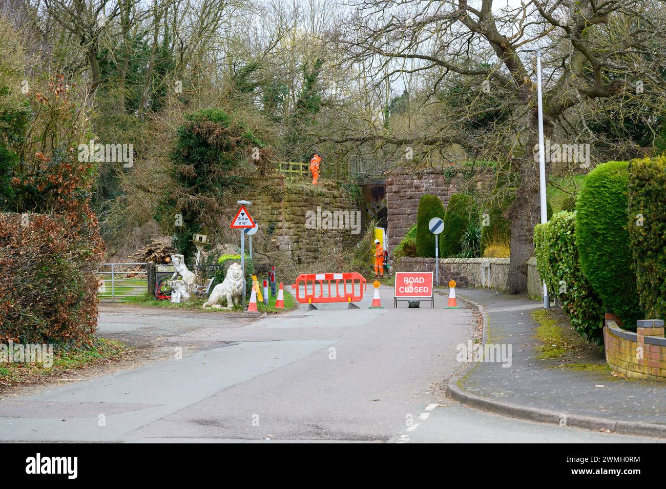 Appaltatori che lavorano su un vecchio ponte ferroviario per eliminare il vegitaion e scrub dall'area dietro un cartello di chiusura stradale. Foto Stock