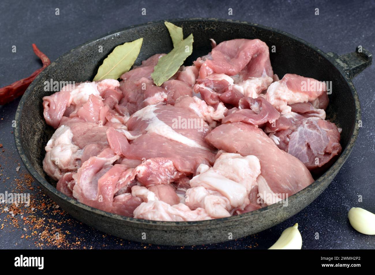 Vista dall'alto di una padella su cui giace carne di maiale tagliata a pezzi, pronta per la cottura. Foto Stock