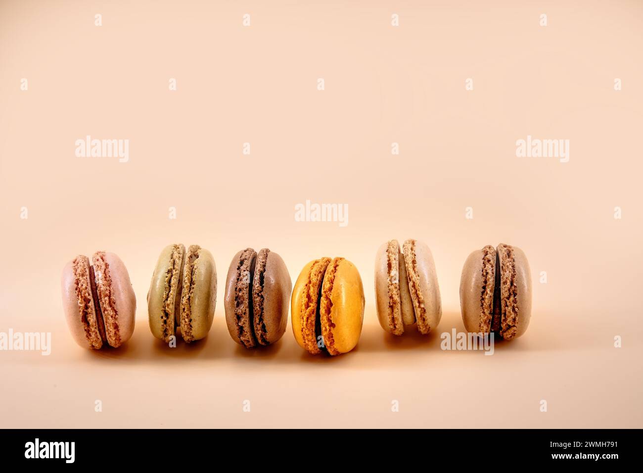 Macaron francesi marroni e arancioni su una tavola di legno Foto Stock