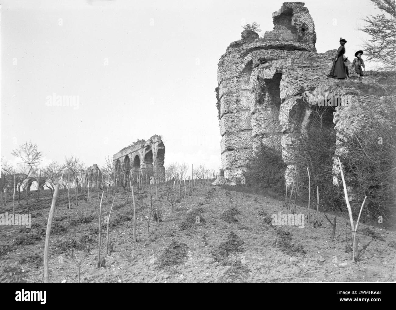 Un gruppo di uomini e donne accanto alle rovine di un ponte dell'impero romano nel sud-est della Francia. Inizio del XX secolo. Vecchia fotografia restaurata dalla lastra di vetro. Foto Stock