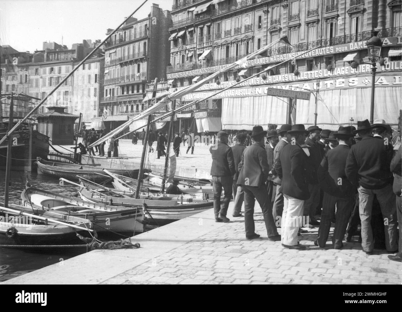Francesi da Cannes vicino a un porto marittimo con barca a vela e nave nel sud-est della Francia. Inizio del XX secolo. Vecchia foto digitalizzata. Foto Stock
