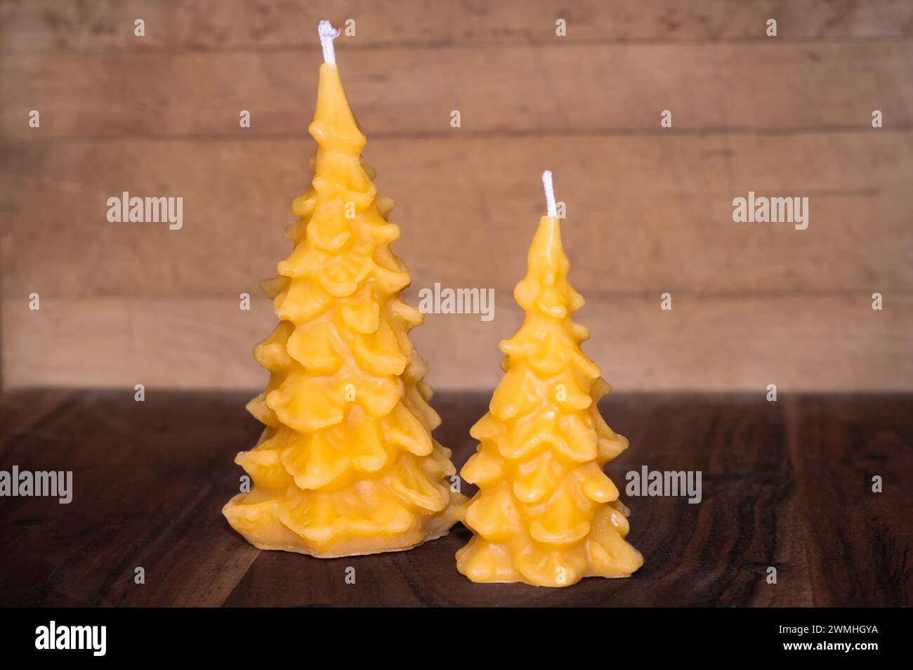 Due candele di cera di api a forma di pini, sfondo in legno Foto Stock