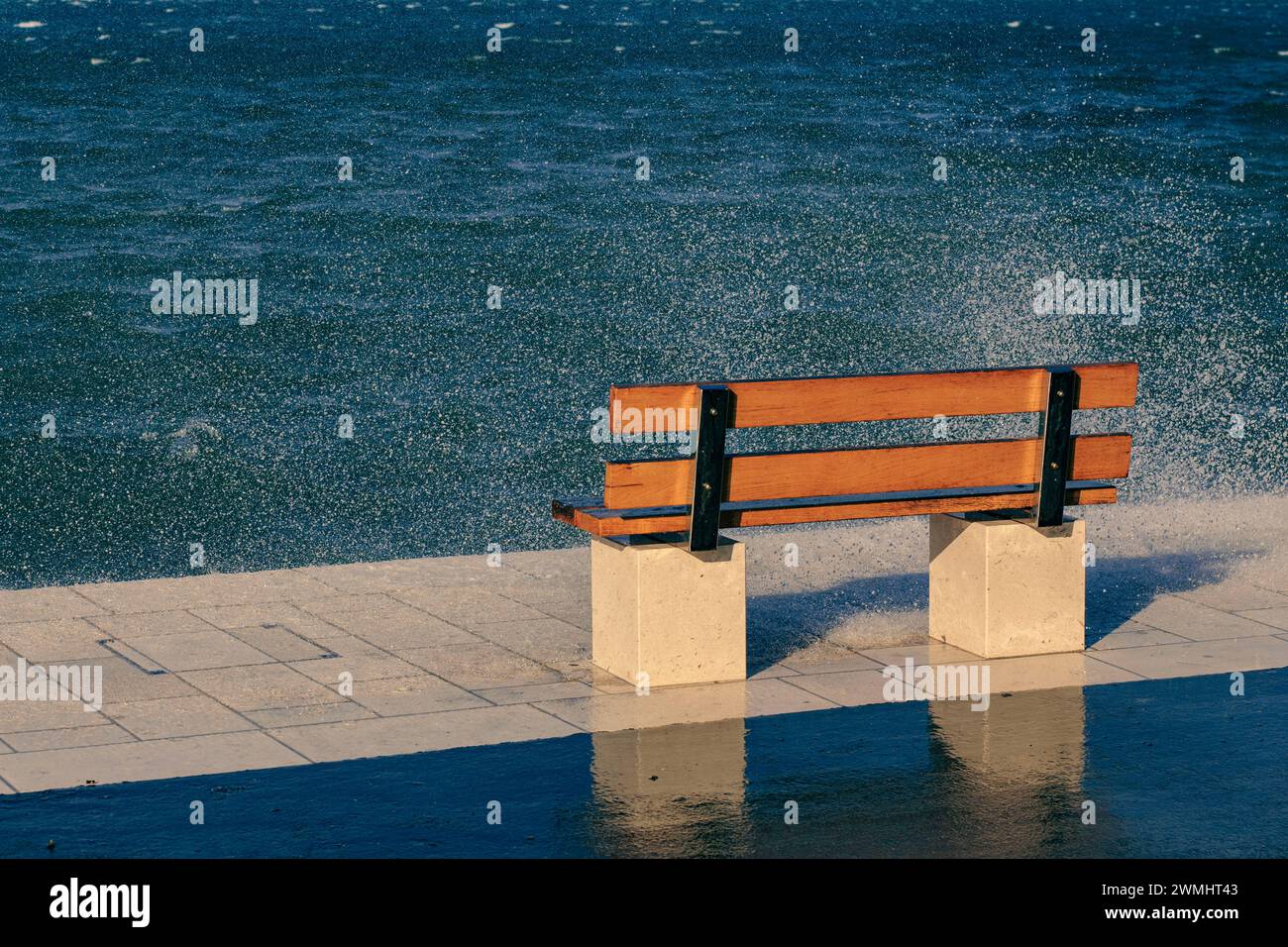 una panchina sul mare ondulato Foto Stock