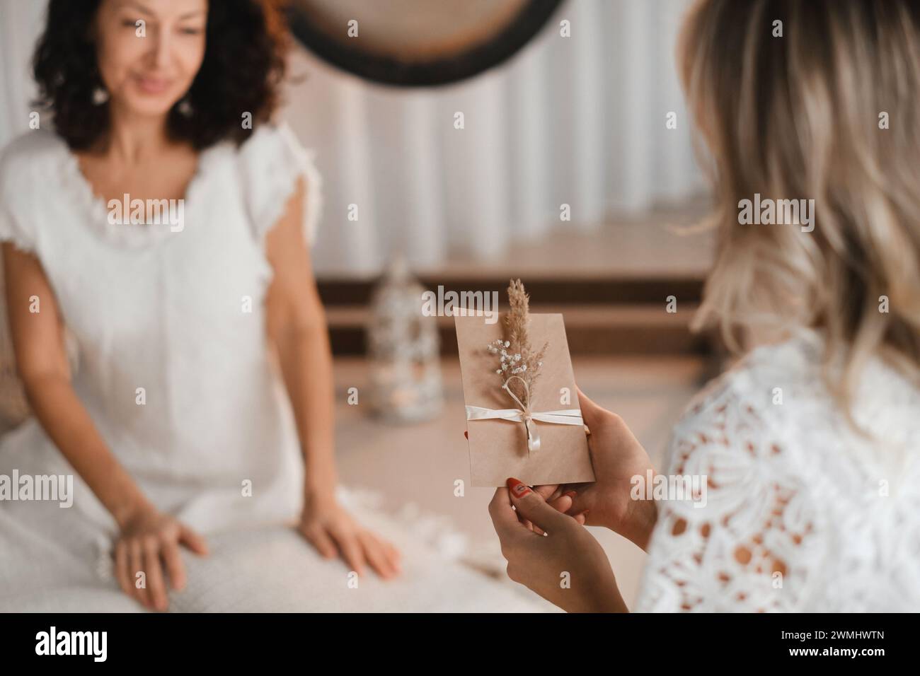 Una donna in abiti bianchi tiene una busta con un desiderio tra le mani. Il concetto di cerchio femminile. Foto Stock