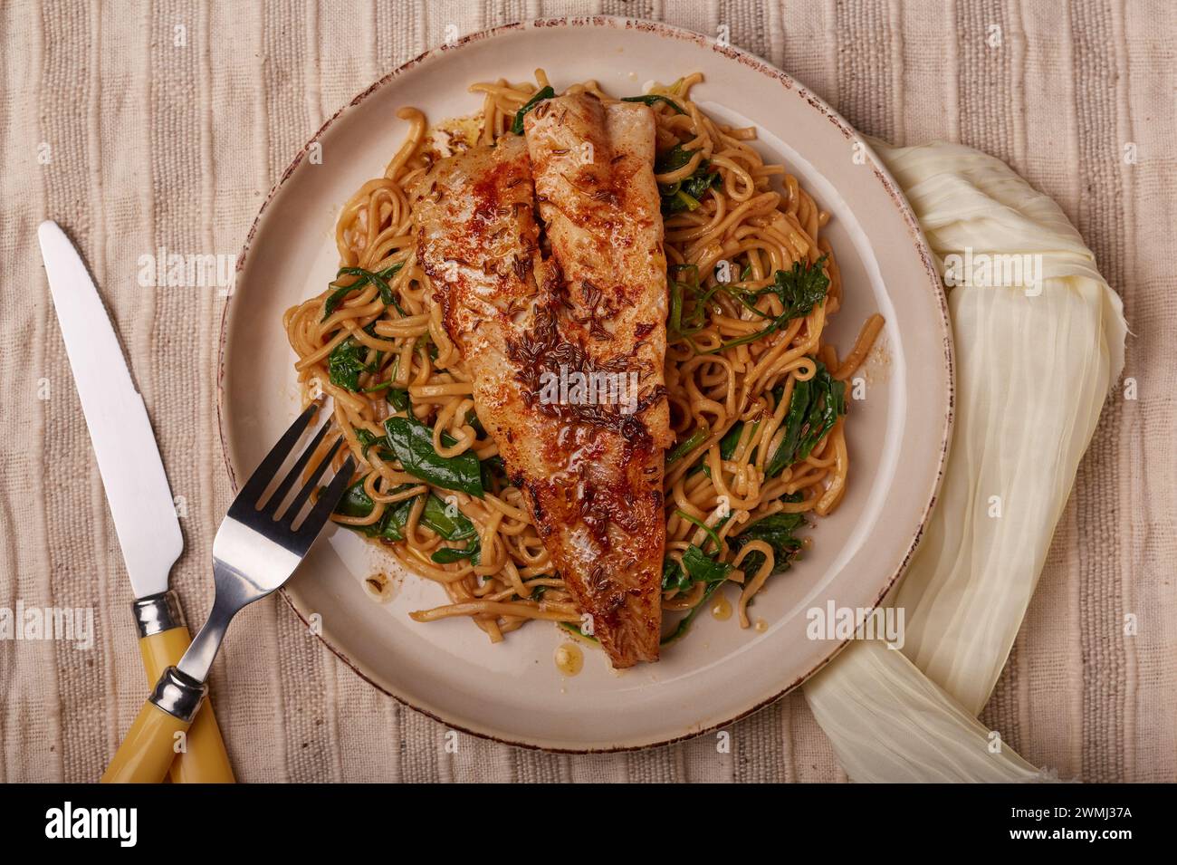 Cuocere in padella il pesce bianco scottato su un letto di spaghetti di spinaci. Foto Stock