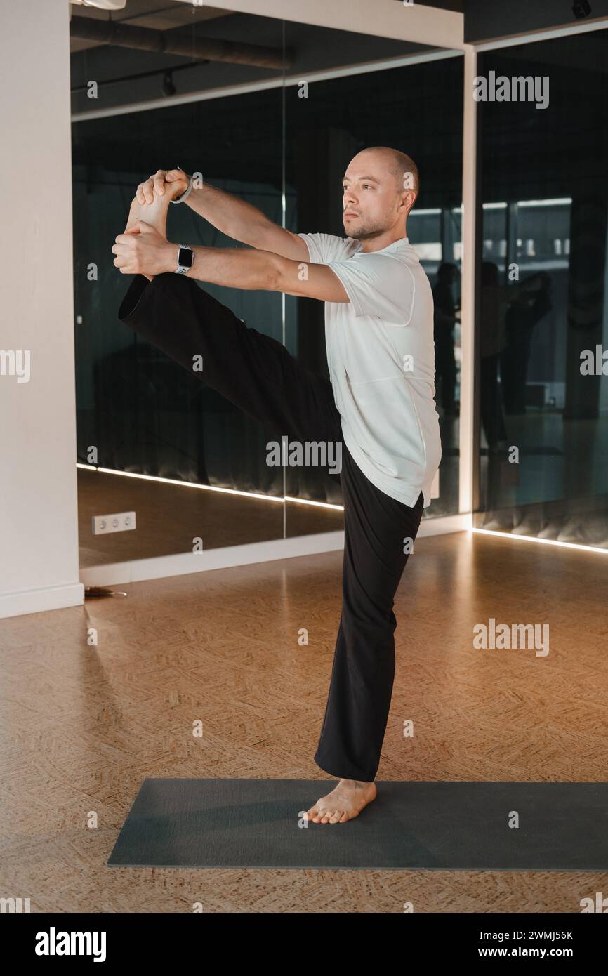 Un giovane atletico fa esercizi nella sala fitness. Un ragazzo professionista fa yoga in palestra. Foto Stock
