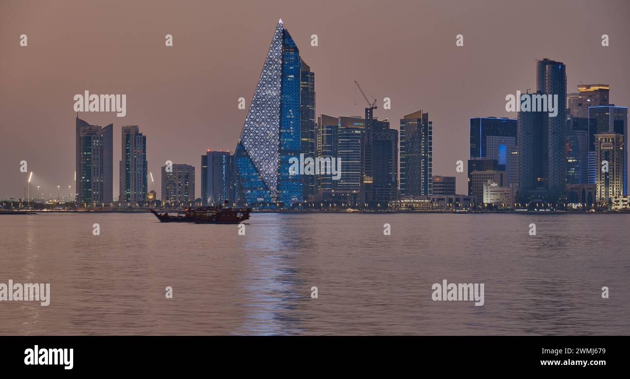 Doha, skyline del Qatar di notte con dhow e barche nel golfo arabo Foto Stock