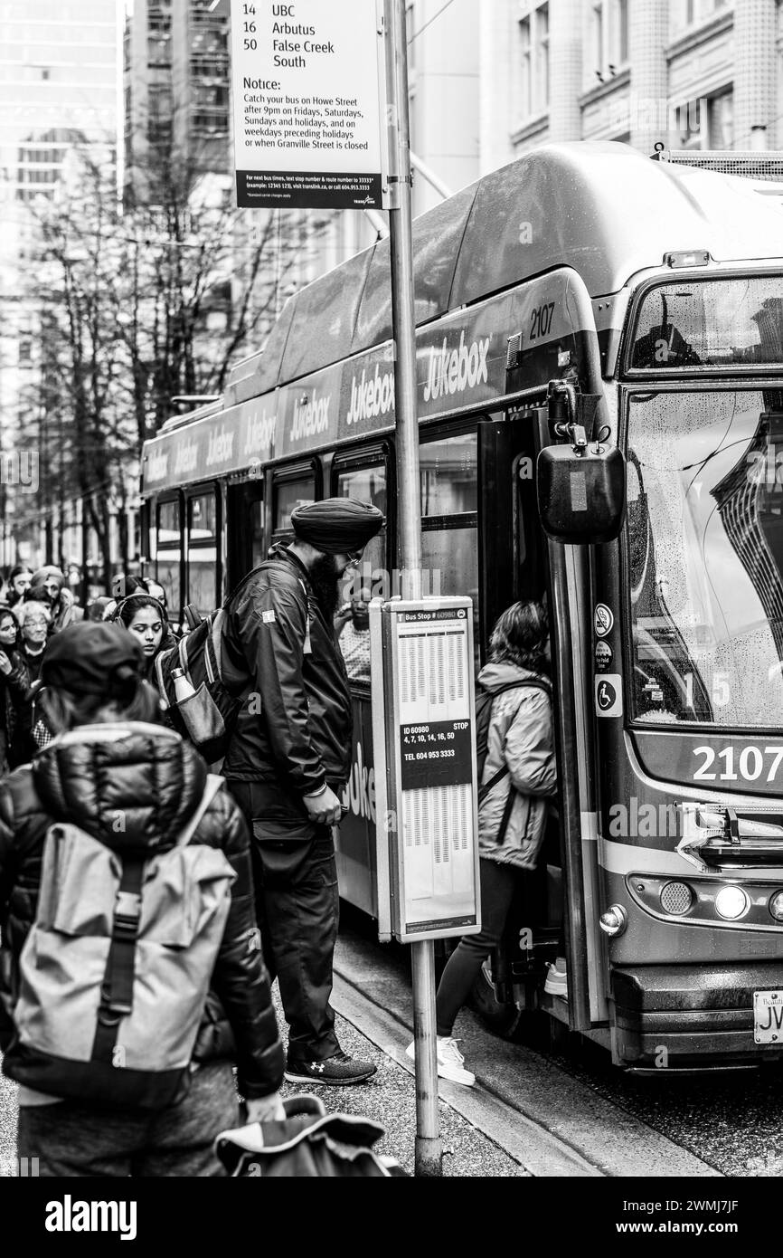 Vancouver, Canada - 21 febbraio 2024: Una foto in bianco e nero di persone che salgono su un autobus a una fermata di Granville Street. Ci sono molte persone che aspettano dentro Foto Stock