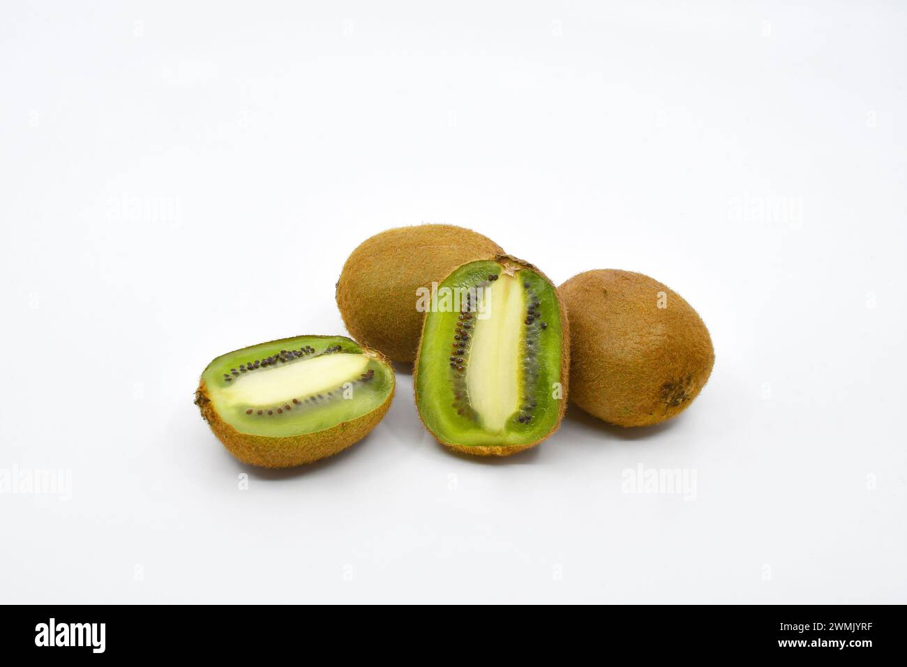 Kiwi tagliati a metà con due kiwi interi su fondo bianco. Copia spazio. Foto Stock