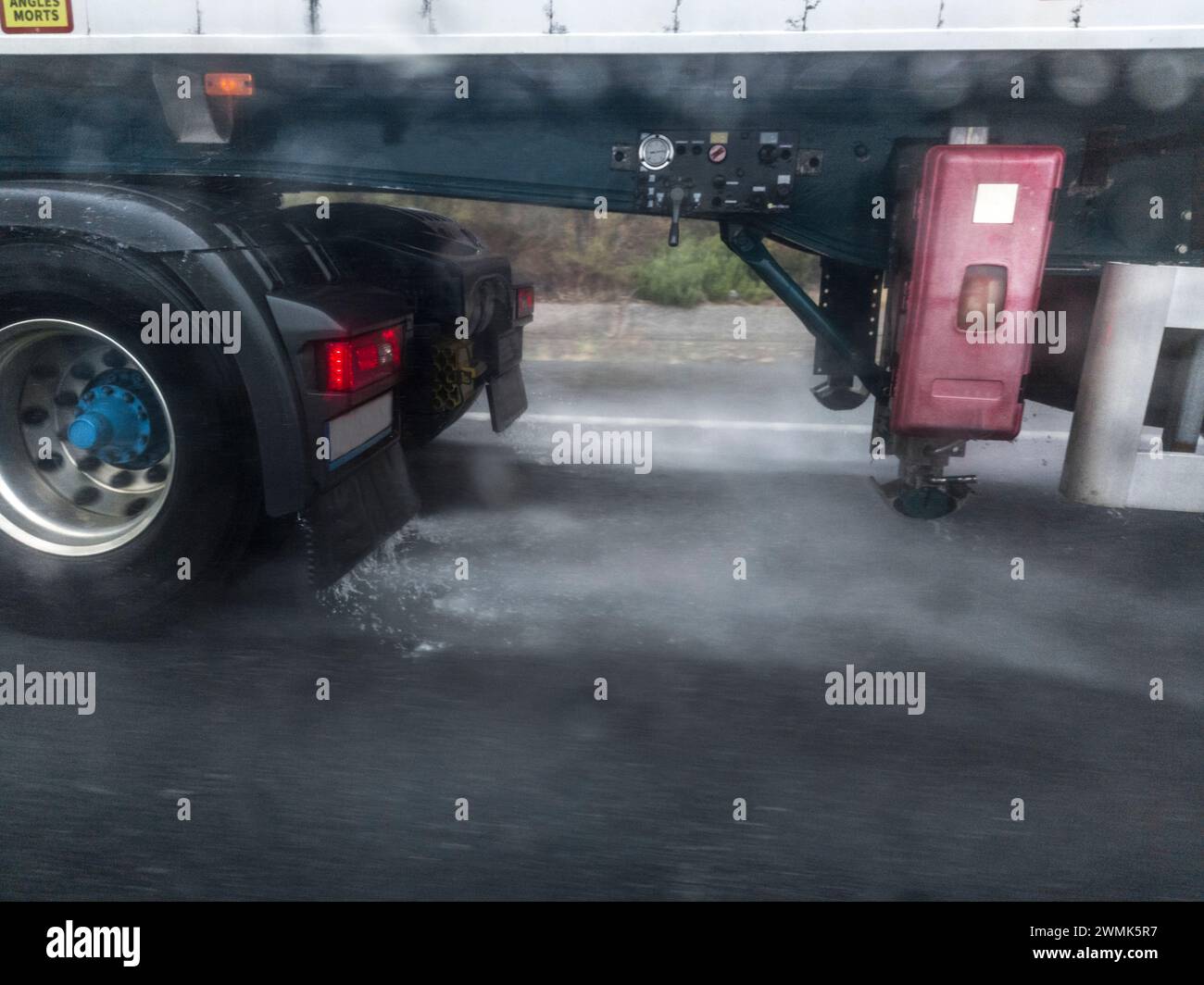 Le ruote del camion spruzzano acqua su strada. Pericoli durante la guida in prossimità di autocarri Foto Stock