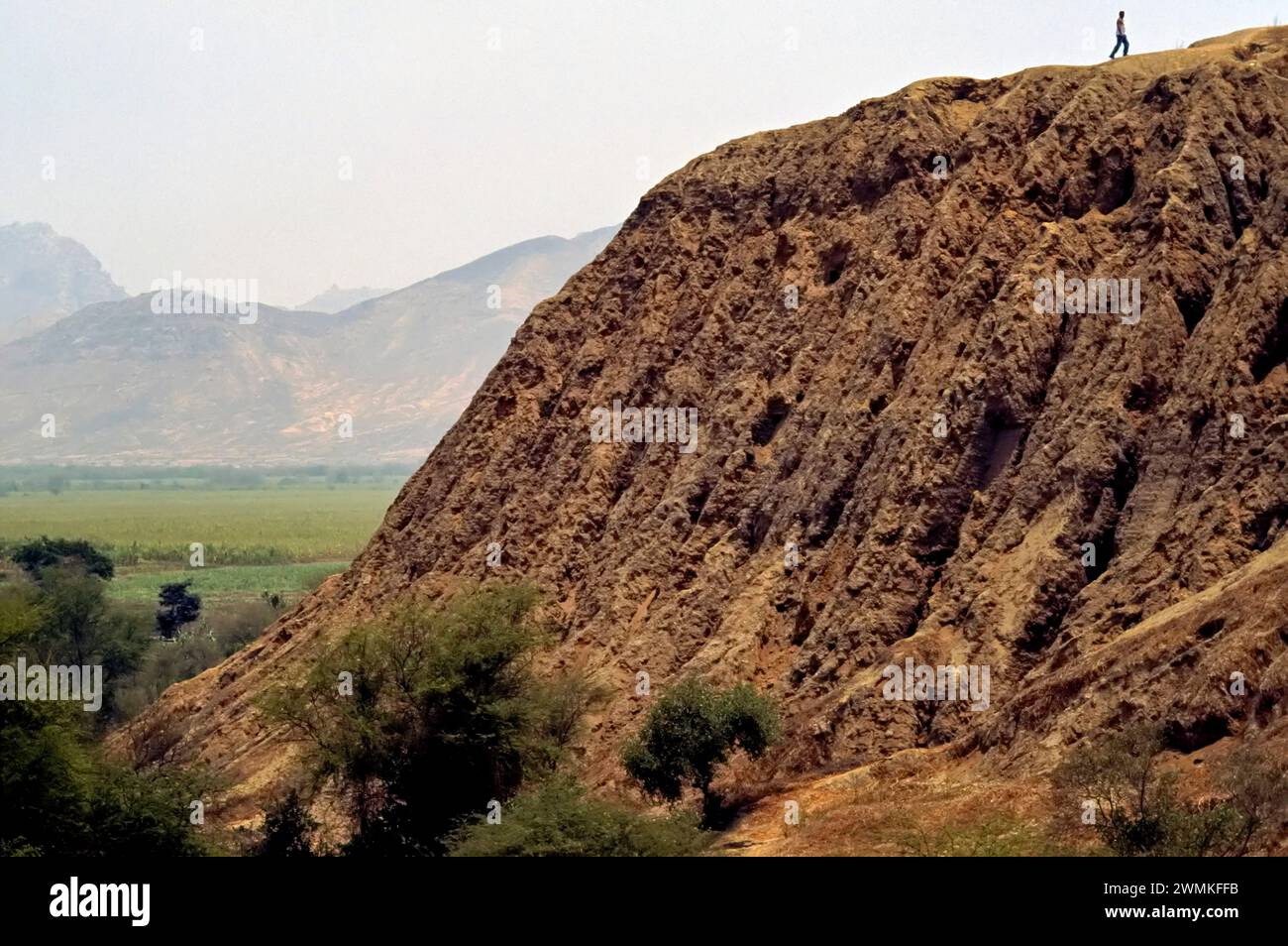 Il turista cammina sulla cima di una piramide usurata sopra una tomba e un sito archeologico. L'Huaca Rajada, di Sipán, in Perù, è una piramide Moche vicino a Chiclayo, per... Foto Stock