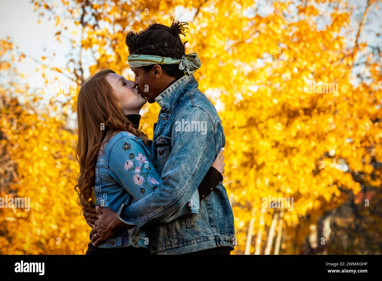 Primo piano di una coppia di sposi che si baciano durante un'uscita di famiglia autunnale in un parco cittadino, trascorrendo del tempo insieme Foto Stock