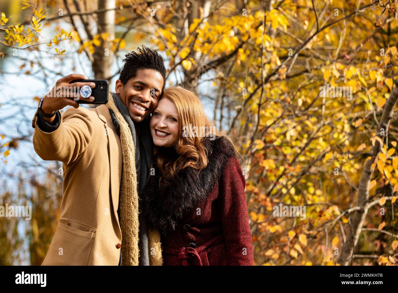 Primo piano di una coppia sposata che si fa un selfie mentre trascorre del tempo insieme durante una gita in famiglia autunnale in un parco cittadino Foto Stock