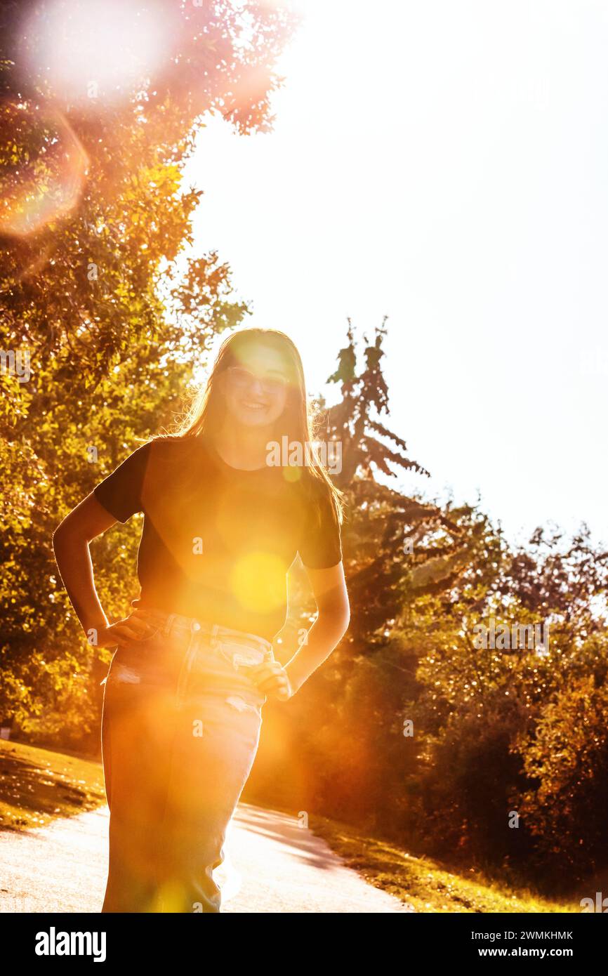 Ritratto all'aperto di una bella ragazza adolescente in un parco cittadino in un caldo pomeriggio autunnale, con brillanti lenti che illuminano l'immagine; Leduc, Alberta, Canada Foto Stock