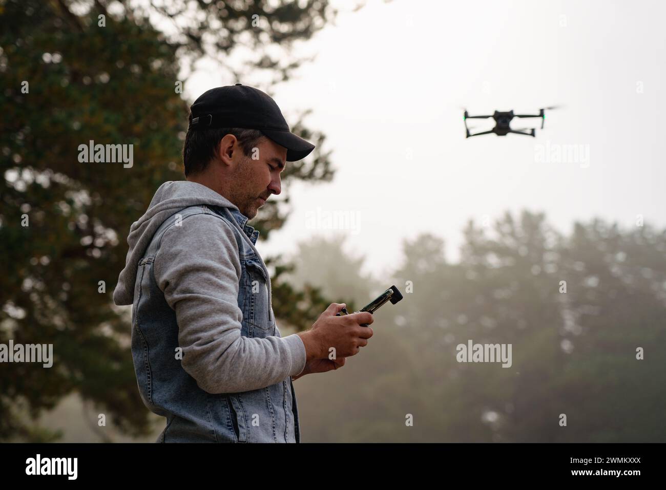 Fotografo professionista che scatta foto dal drone. uomo che scatta foto aeree nella foresta. Uomo che controlla il suo drone sullo sfondo della foresta di montagna. Foto Stock