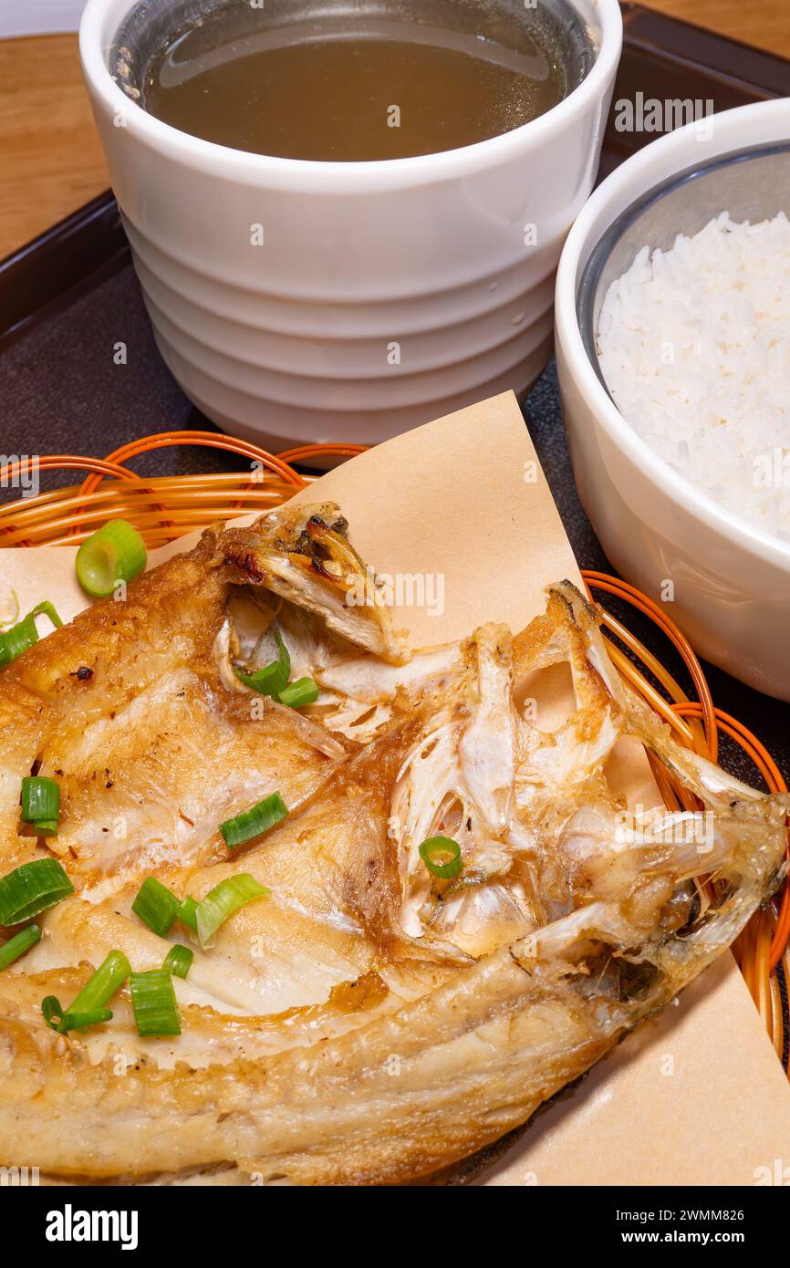 vista angolare spigola fritta fresca e riso e zuppa di pollo tenero stufato con ginseng a composizione verticale Foto Stock