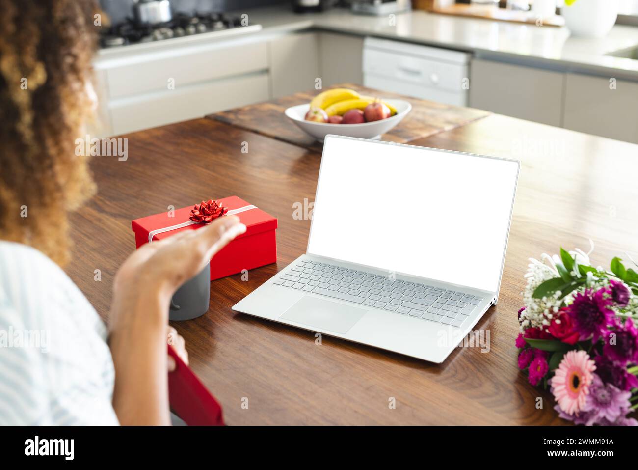 Una donna birazziale gode di un regalo a sorpresa a casa durante una videochiamata online con spazio di copia Foto Stock