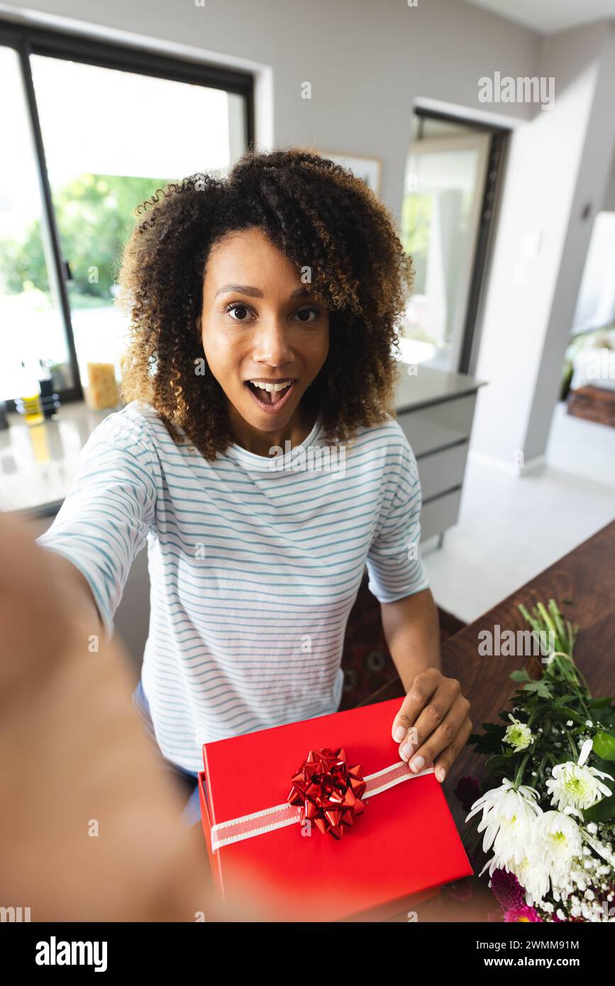 Una donna birazziale riceve un regalo a sorpresa a casa Foto Stock