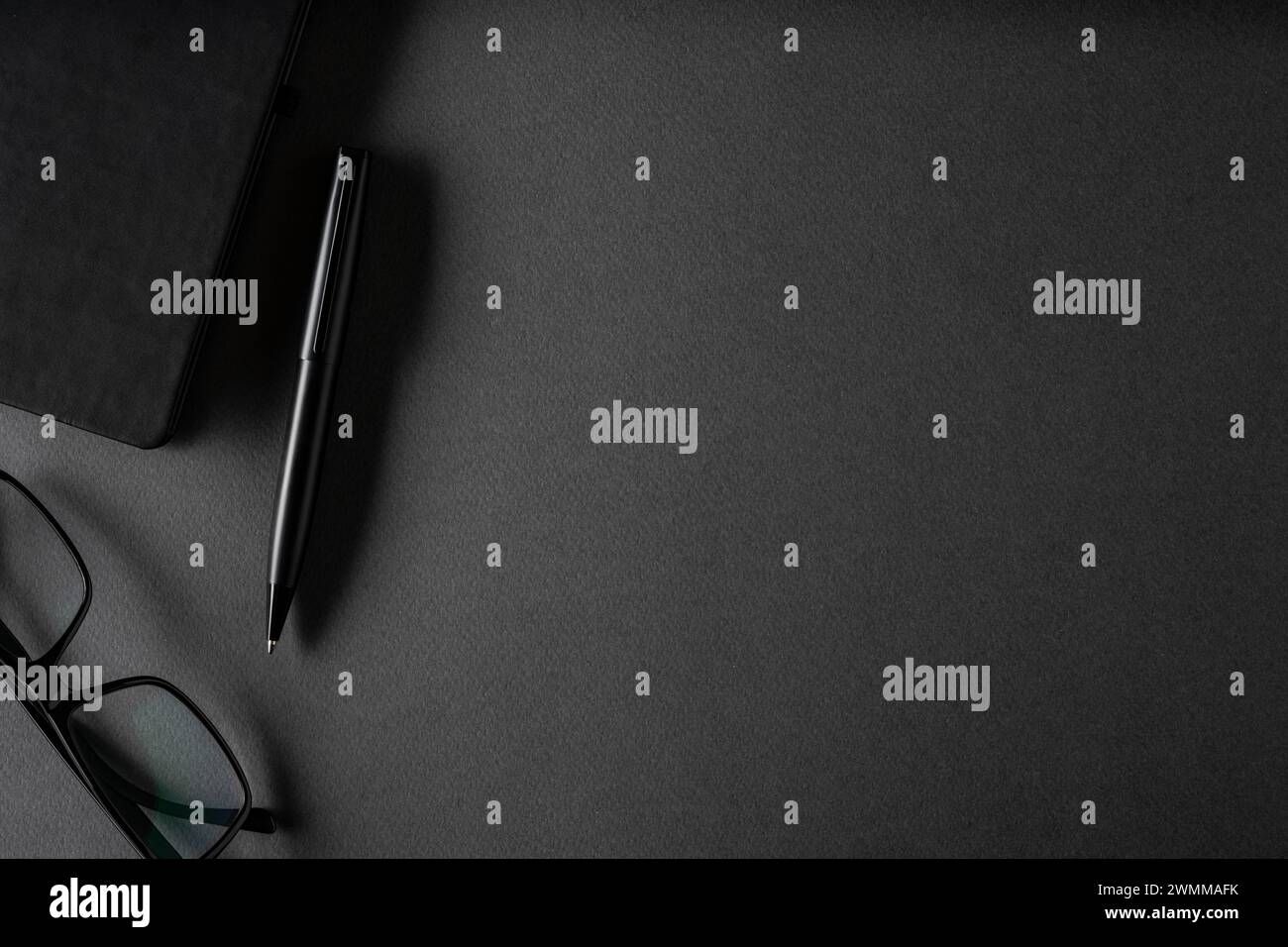 Vista dall'alto della penna a sfera, degli occhiali e del blocco note su un tavolo grigio scuro Foto Stock