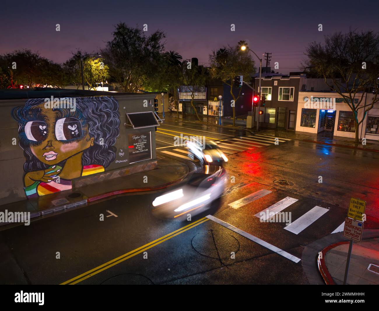 LOS ANGELES, CA - 5 febbraio 2024: Traffico all'incrocio tra Santa Monica Blvd e N Genesee Ave a West Hollywood, guida da graziose ragazze graffiti Foto Stock