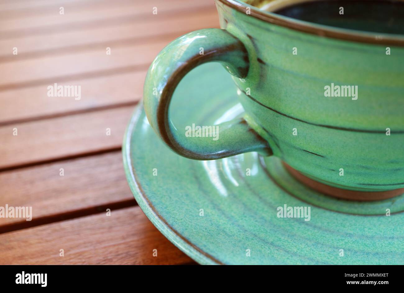 Caffè caldo in una tazza di ceramica verde isolata su un tavolo di legno Foto Stock