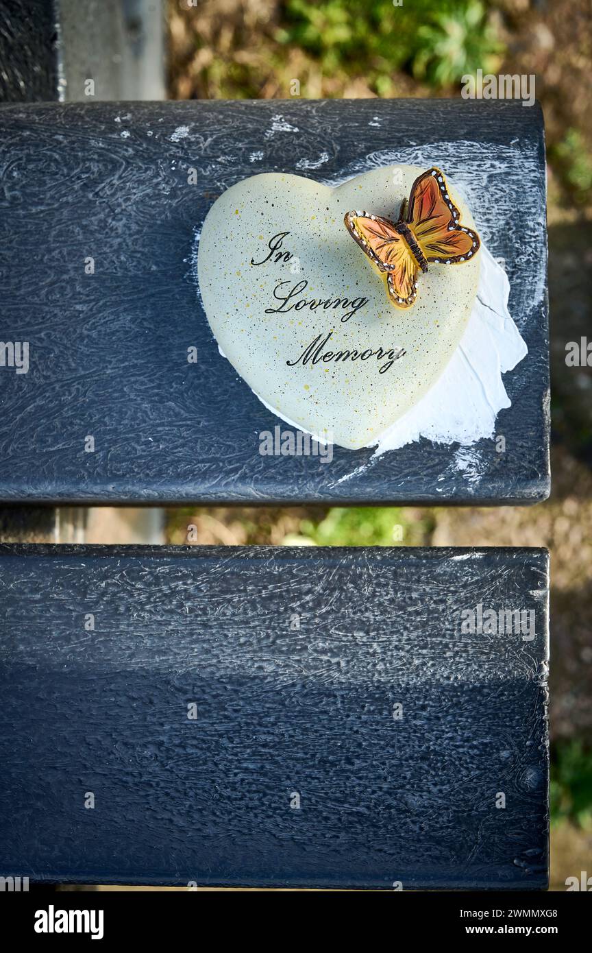 Nella memoria amorevole roccia a forma di cuore e farfalla sulla panca del parco Foto Stock