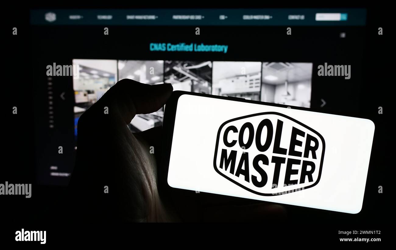 Persona che detiene un telefono cellulare con il logo della società taiwanese Cooler Master Technology Inc. Di fronte alla pagina Web aziendale. Mettere a fuoco il display del telefono. Foto Stock
