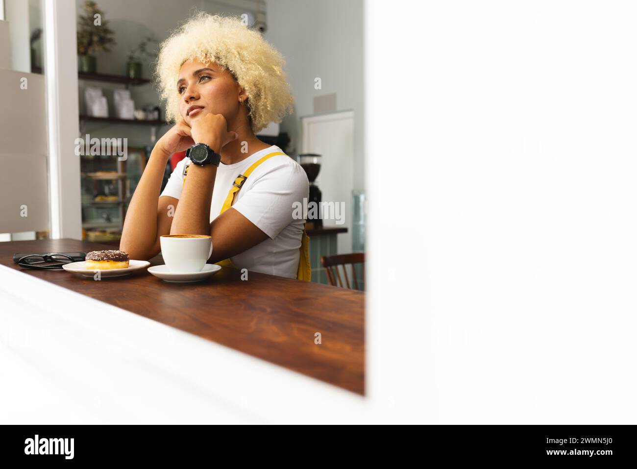 La giovane donna birazziale gode di un momento di contemplazione in un bar, con spazio per le copie Foto Stock