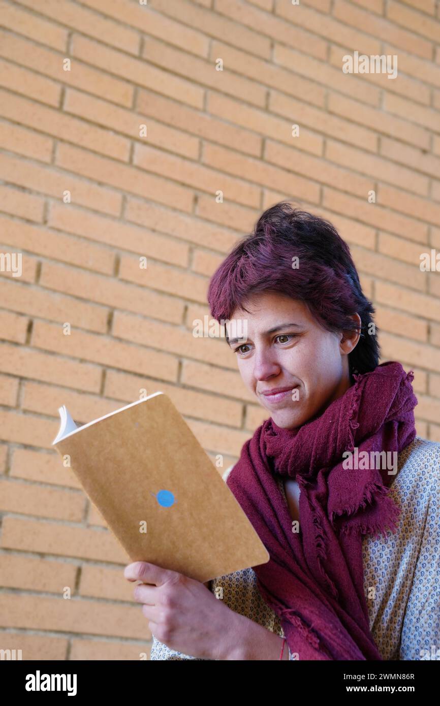 Donna concentrata che legge un libro per strada. Giorno di San Giorgio. Diada de Sant Jordi Foto Stock