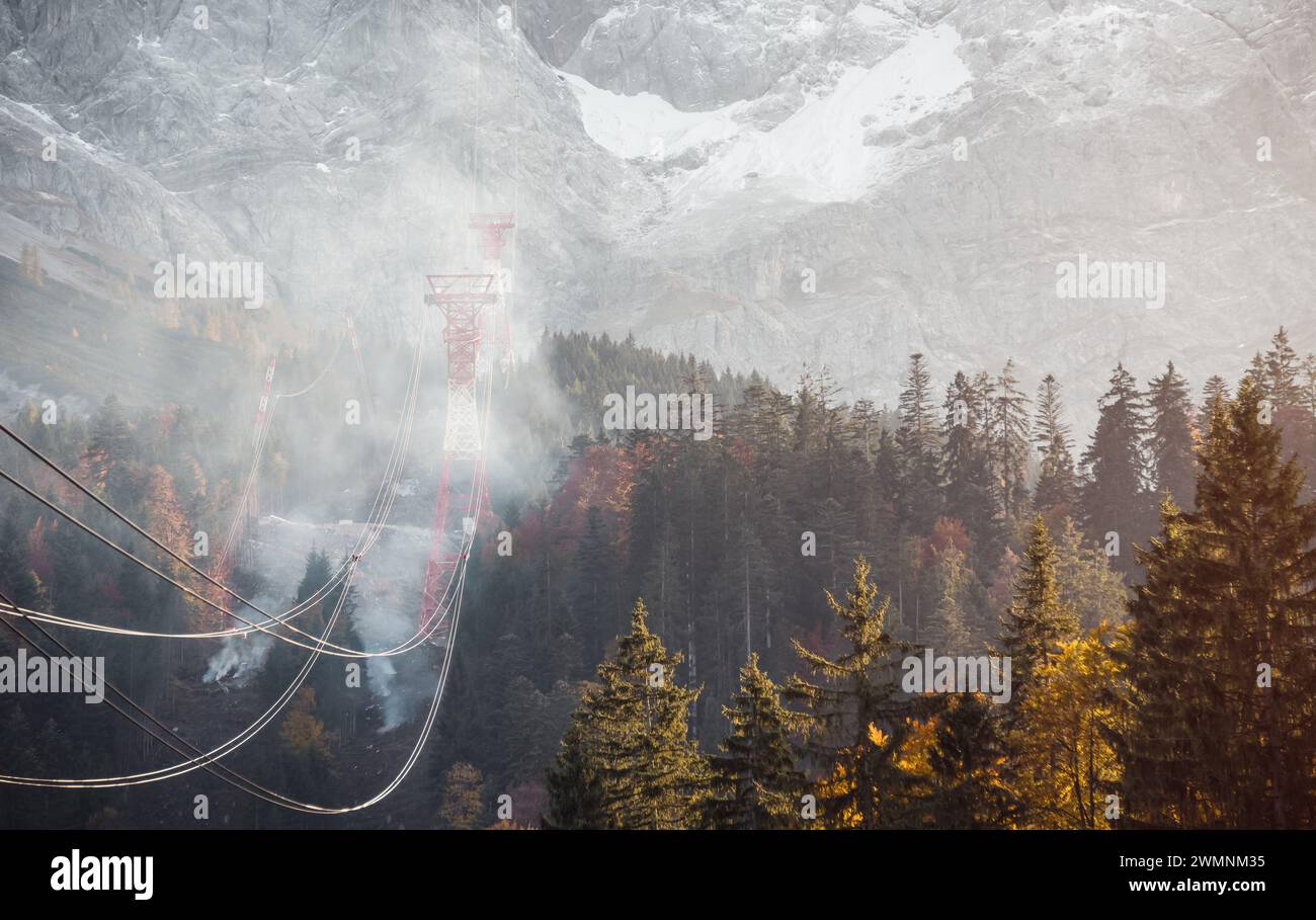 Cavi di funivia alpina che attraversano la foresta ricoperti di fumo. Foto Stock