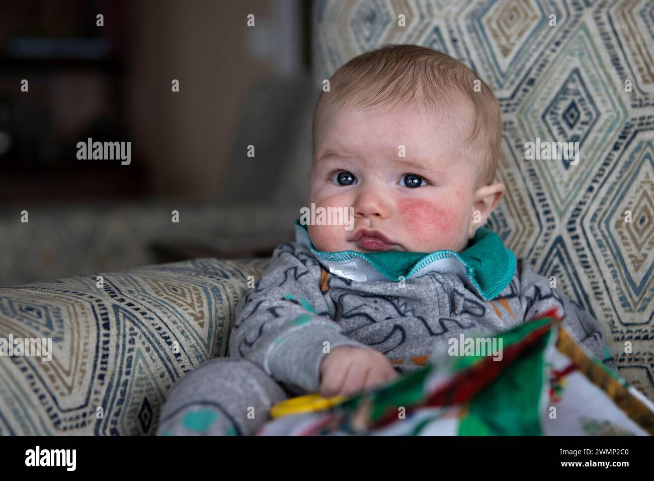 Bambino di quattro mesi appoggiato su una sedia. Foto Stock