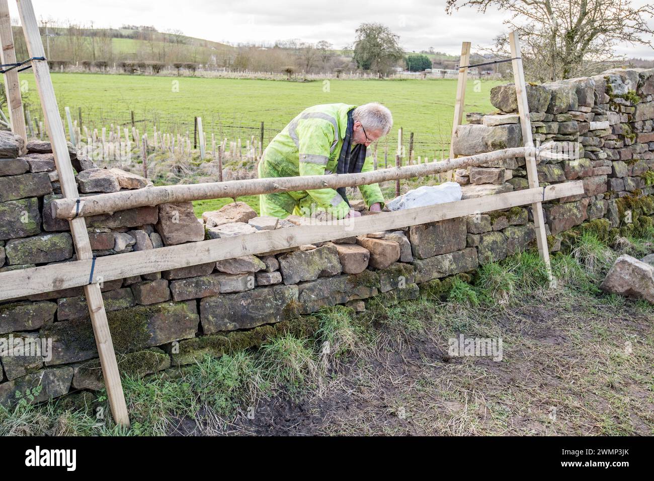 Il volontariato assume ogni forma e qui qualcuno sta generosamente donando tempo e sforzi per ricostruire un muro sul canale di Leeds e Liverpool, Gargrave Foto Stock