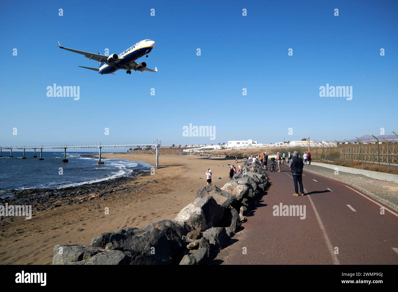 I turisti al recinto perimetrale di playa lima presso l'aeroporto ACE arrecife osservano gli aerei ryanair boeing 737 che arrivano a landLanzarote, Isole Canarie, sp Foto Stock