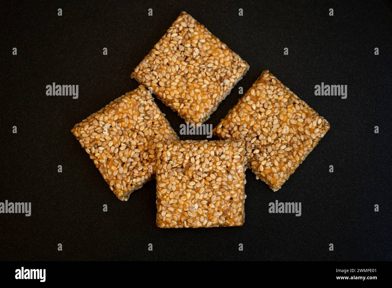 Til chikki su sfondo grigio nero. Il til chikki è un dolce indiano preparato con gesso e sesamo. Festa indiana makar sankranti dolce speciale Foto Stock