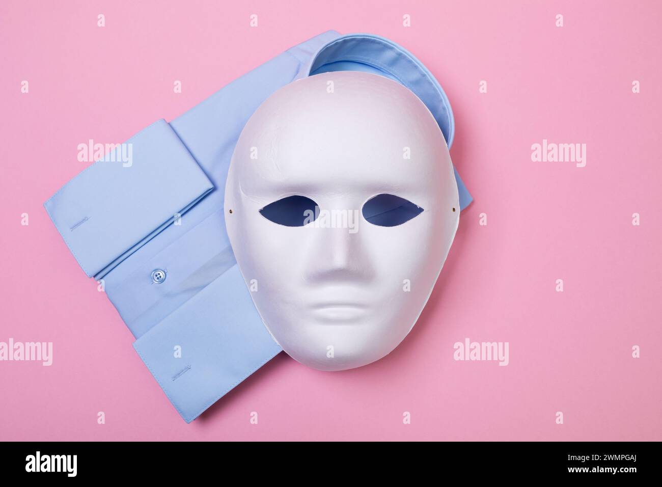 Vista dall'alto della maschera bianca e della camicia su sfondo rosa, concetto sui prodotti contraffatti e falsi Foto Stock
