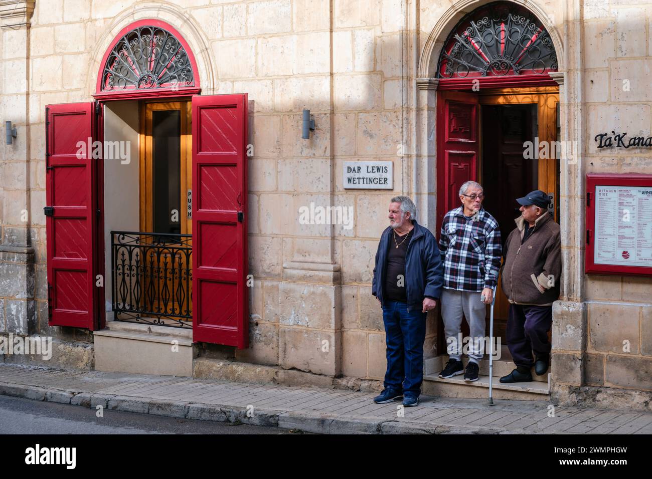 Uomini che chiacchierano in una porta, Mellieha, Malta Foto Stock