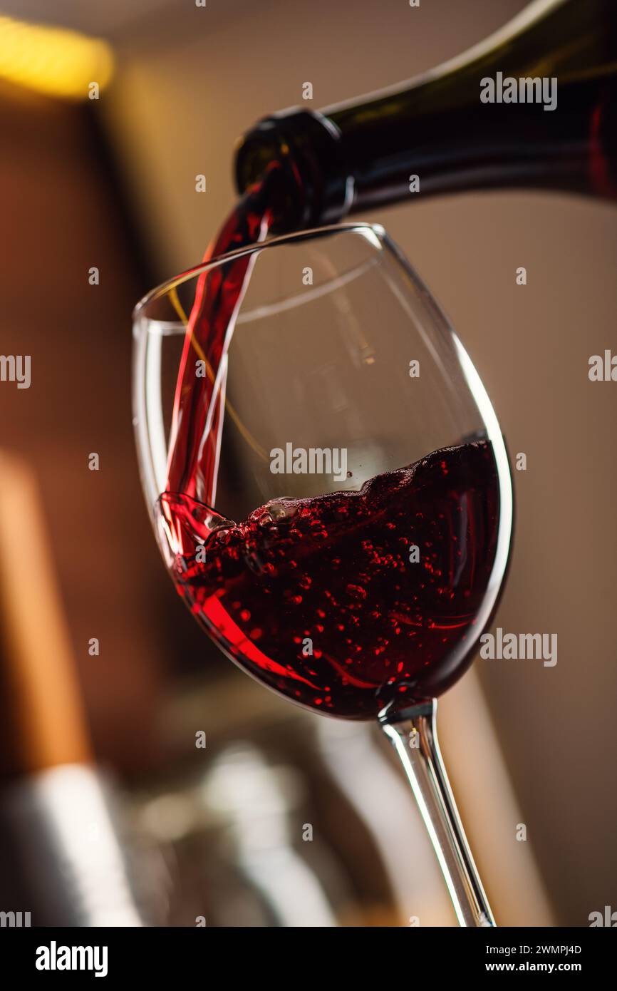 Congela il movimento con il vino rosso versato nel bicchiere con spruzzi Foto Stock
