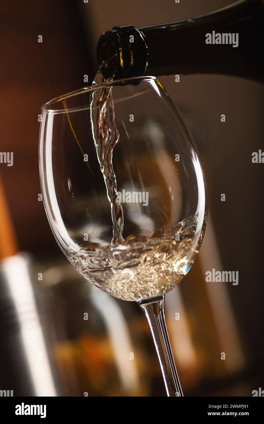 Freeze Motion con vino bianco francese che si versa in un bicchiere di bollicine con uno spruzzo sul tavolo in cucina, uno studio di alta qualità primo piano Foto Stock