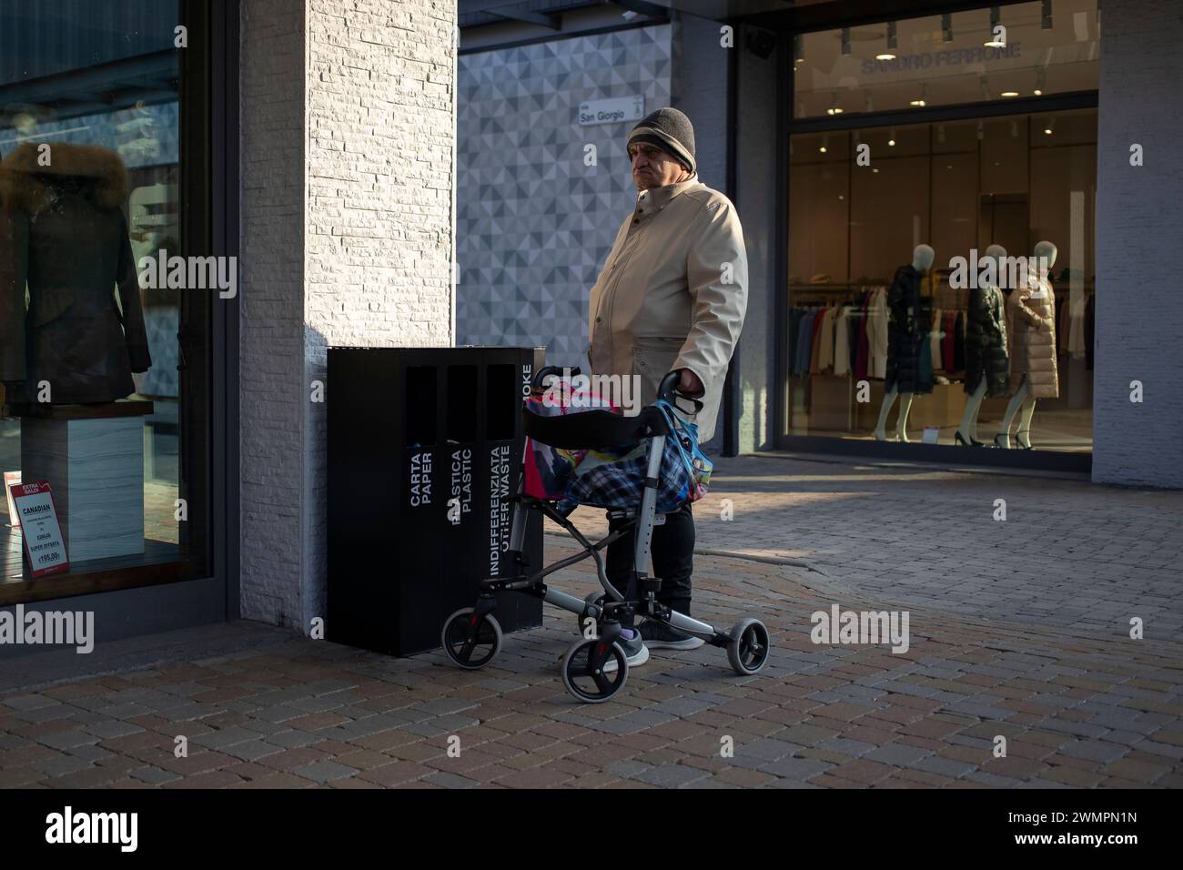 Novara, Italia, 16 gennaio 2024: Un anziano gentiluomo che usa un rollator a ruote si prende una pausa nel centro commerciale Foto Stock