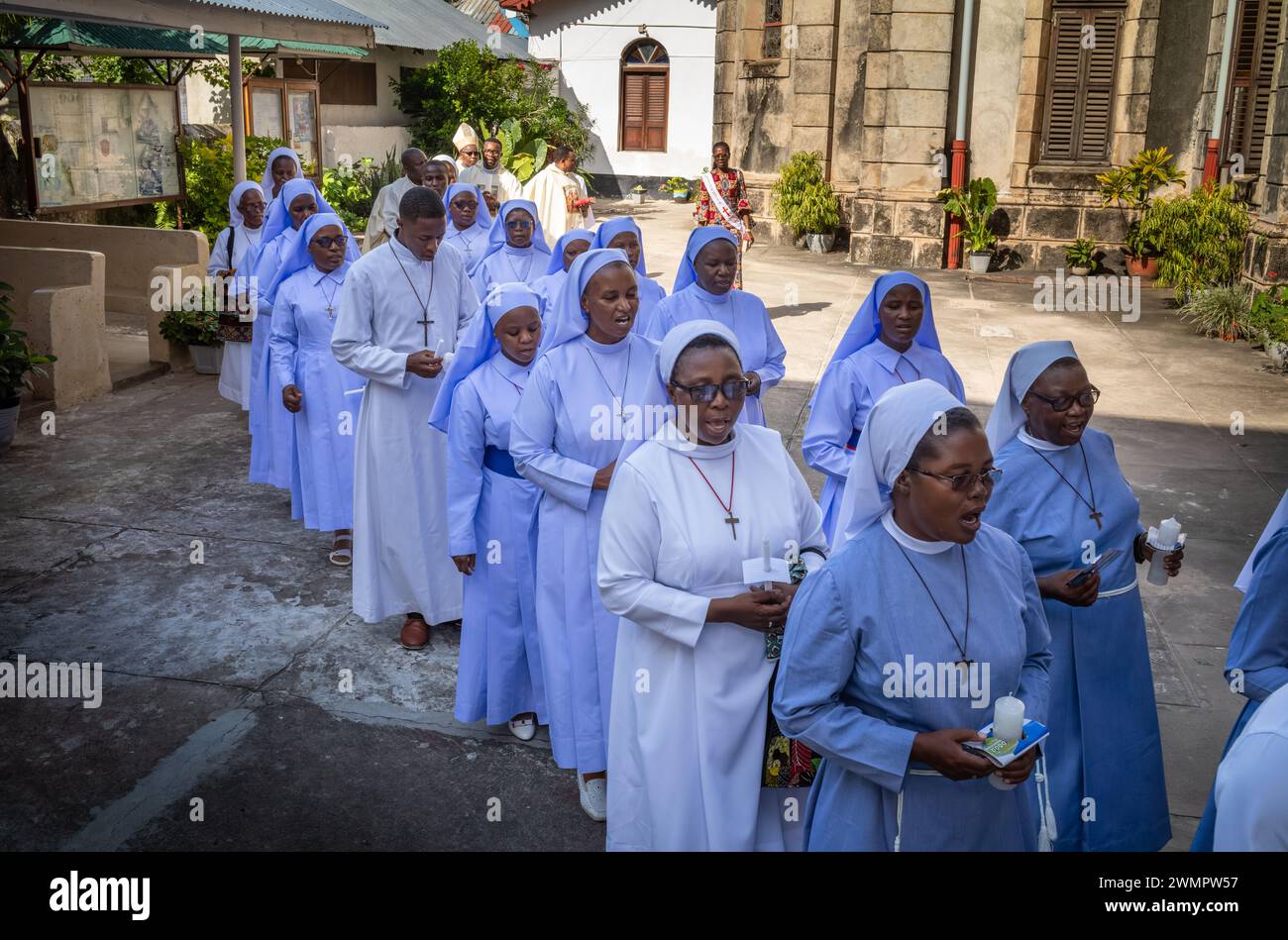 Suore e seminaristi cattolici cantano mentre entrano nella Cattedrale di San Giuseppe per la messa domenicale cattolica a Stone Town, Zanzibar, Tanzania. Foto Stock