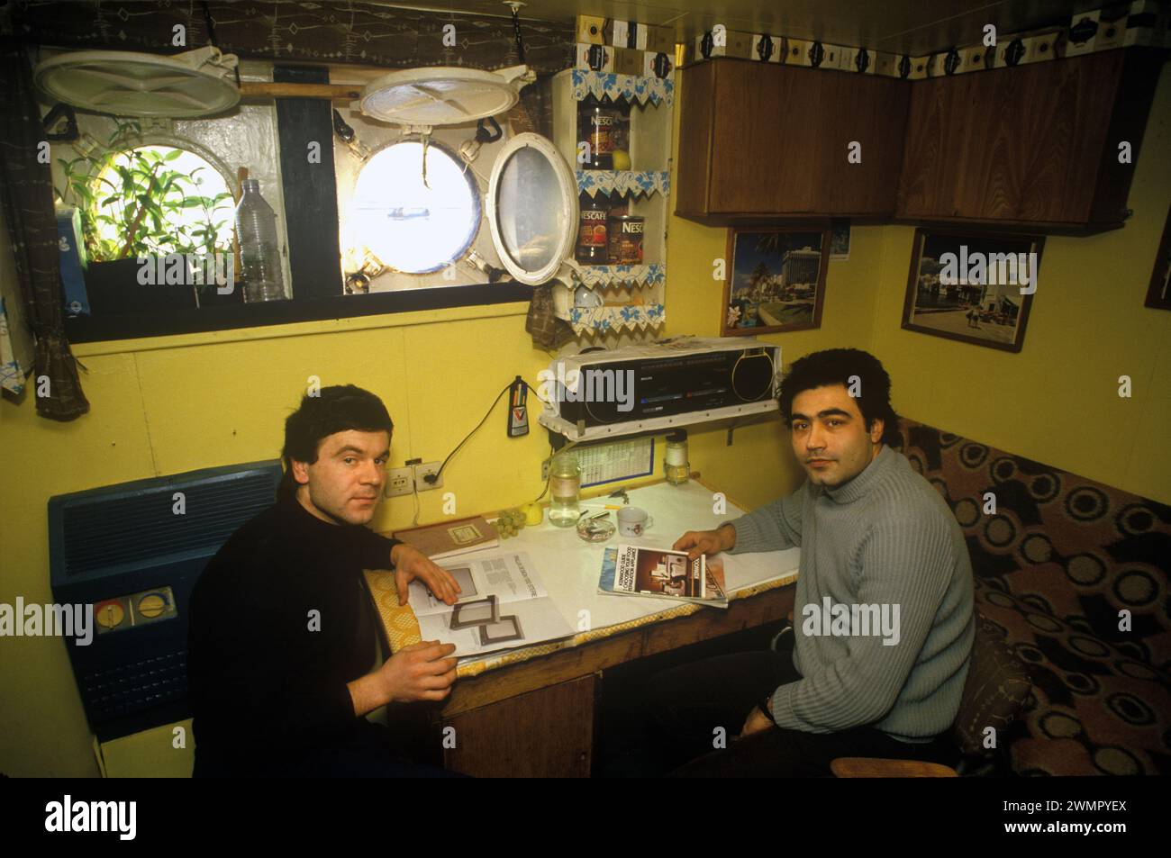 Klondykers - fabbrica di pescatori dell'Europa orientale, pescatori, pescherecci, anni '1980, Regno Unito. Interno della barca da pesca di fabbrica pescatori bulgari in cabina leggendo un manuale di progettazione Finlux e una guida Kenwood per la scelta dell'apparecchio per la preparazione degli alimenti. 1986 Ullapool Scotland HOMER SYKES Foto Stock