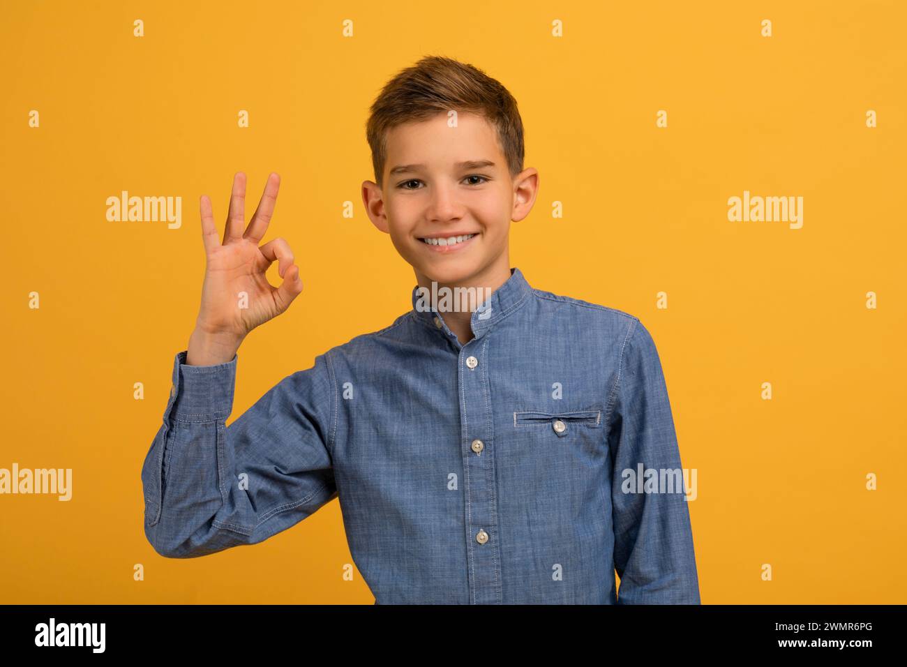 Adolescente sicuro di sé con la camicia blu che fa un gesto perfetto con le dita Foto Stock