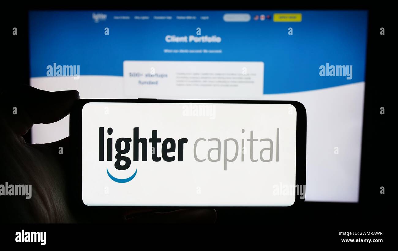 Persona che detiene un cellulare con il logo della società statunitense di servizi finanziari Lighter Capital Inc. Di fronte alla pagina Web aziendale. Mettere a fuoco il display del telefono. Foto Stock